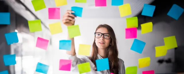 mujer joven viendo una pared transparente con pegatinas de papel