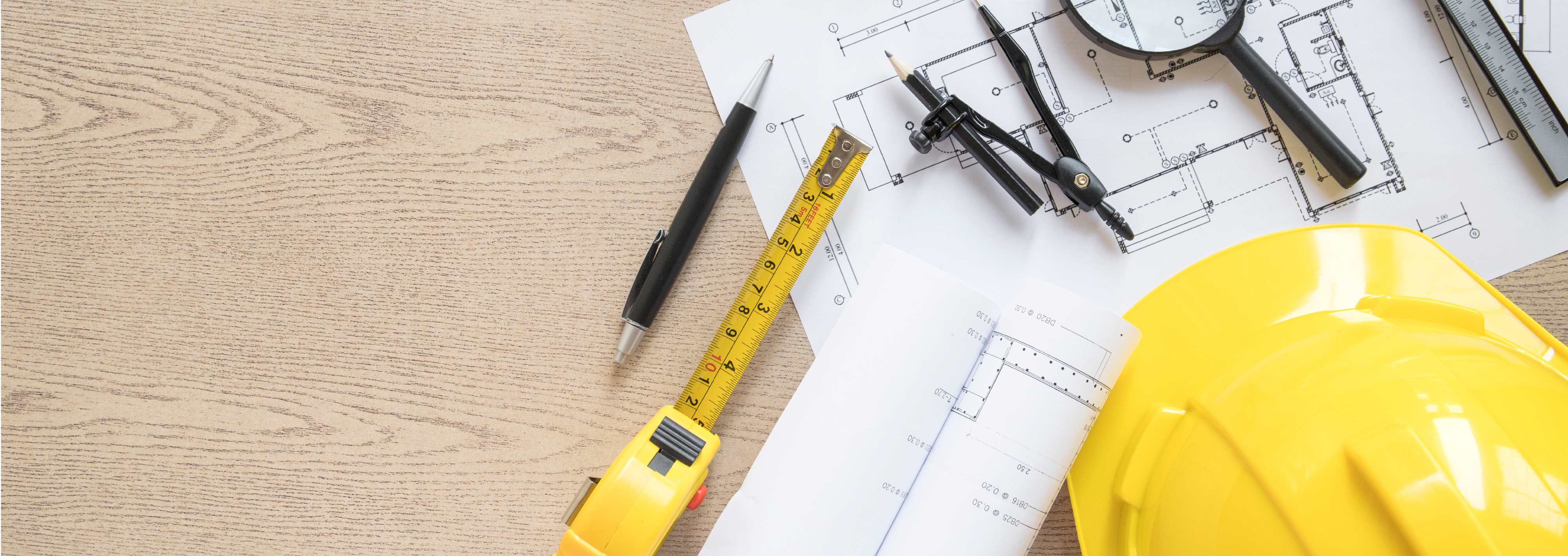 casco de seguridad y herramientas encima de una mesa con un plano a la par