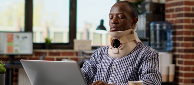 Persona utilizando un cuello ortopédico mientras usa una laptop
