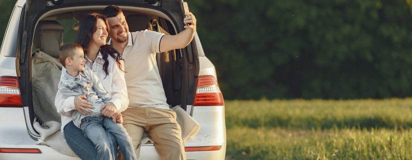 Familia de tres integrantes sentados en la parte posterior del vehiculo tomando foto